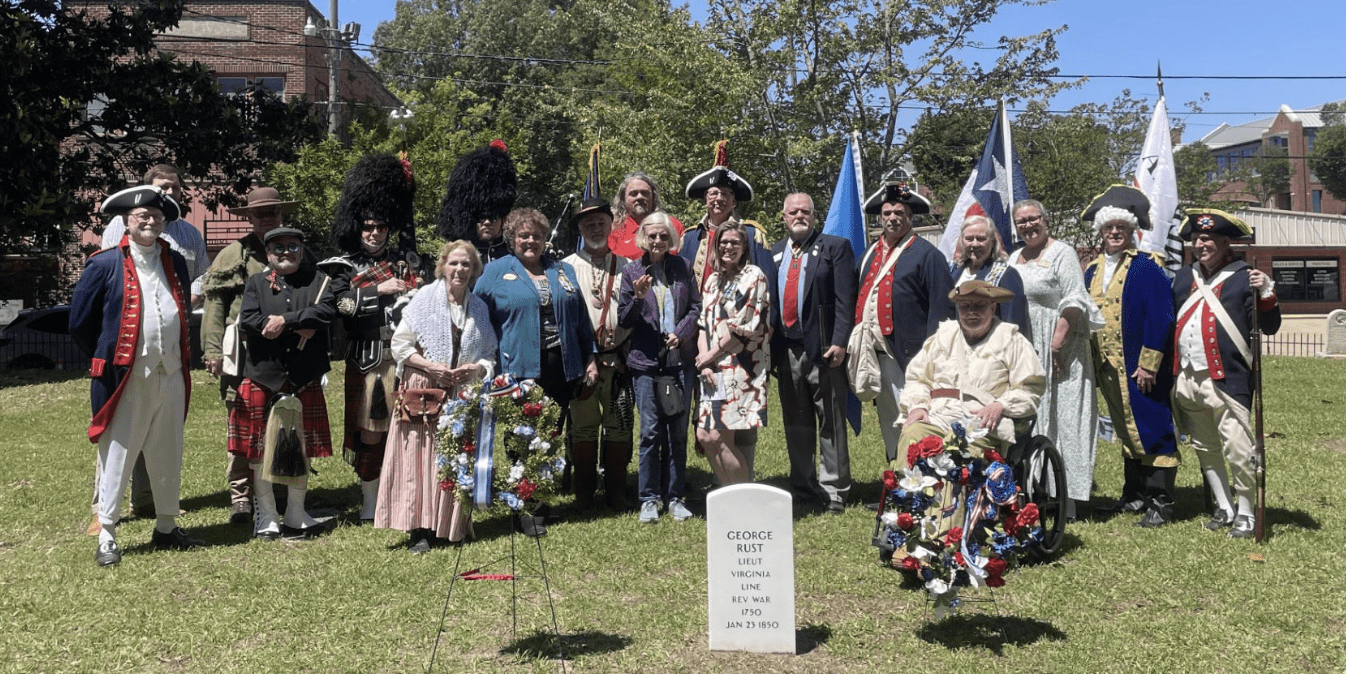 Colonial reenactors at graveside memorial with wreaths